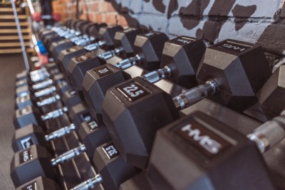 Zbliżenie na rząd profesjonalnych, czarnych hantli heksagonalnych marki HMS, starannie ułożonych na stojaku w Move Yourself Studio Treningowe Zabrze