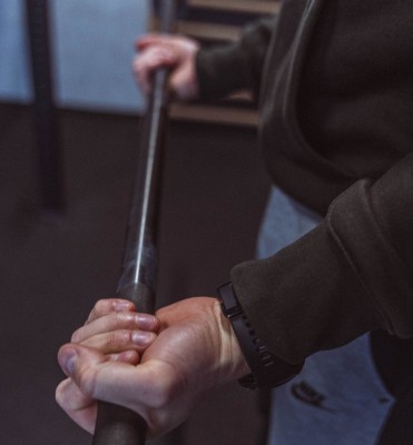 Zbliżenie na dłonie pewnie trzymające sztangę podczas bezpiecznego treningu siłowego w My Studio Zabrze, wspierającego proces odchudzania.